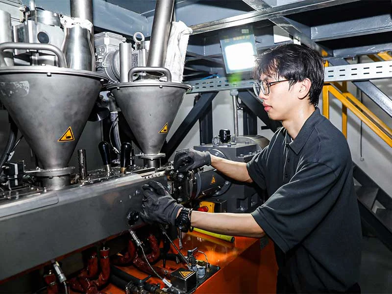 buss-technikum_shanghai-china_prozessentwicklung-fuer-plastik-produktion Mitarbeiter des BUSS Test Centers in China an einem COMPEO LAB Compounder.