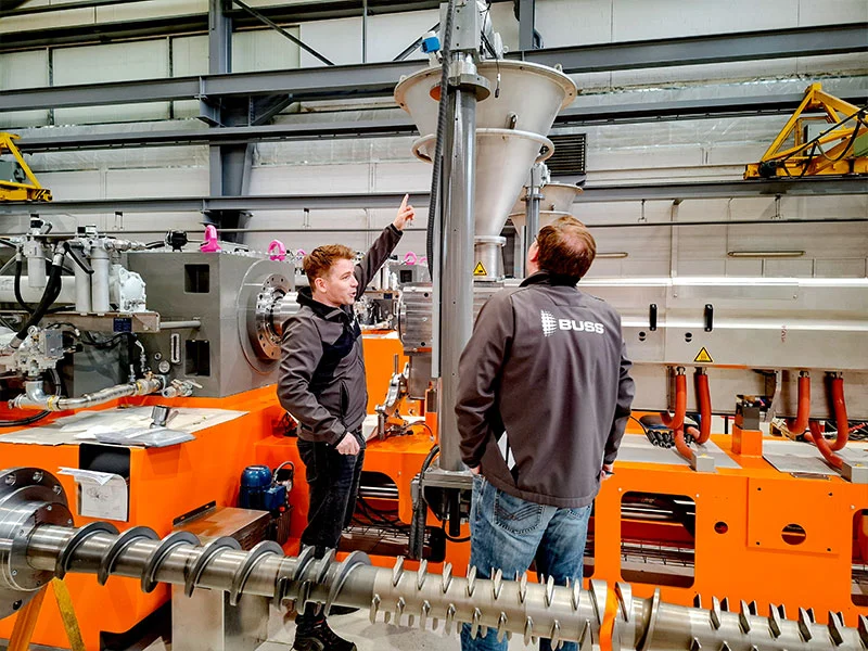 Zwei Kollegen aus dem BUSS Team inspizieren eine COMPEO CIS Inlet Screw im Rahmen der Qualitätsprüfung, um BUSS' Anspruch zu wahren.